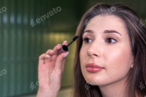 Preview: Young woman applying mascara closeup. Everyday makeup.