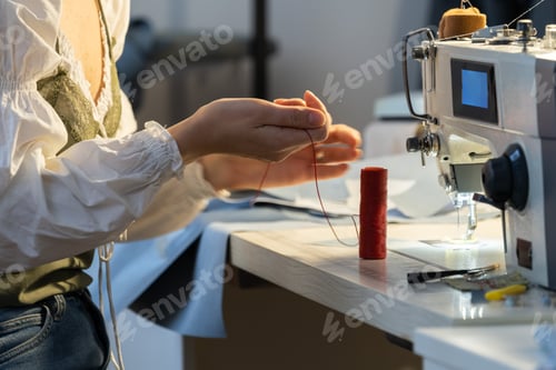 Preview: Young dressmaker female sew on sewing machine. Professional seamstress girl work in tailor workshop