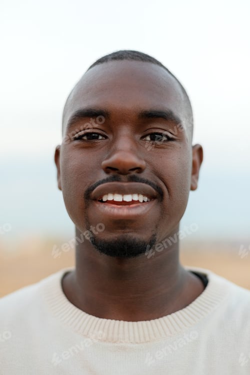Preview: Vertical portrait of young African American man looking at camera. Headshot.