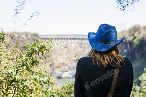 Preview: Rear view of young woman looking out at bridge, Victoria Falls, Zambia