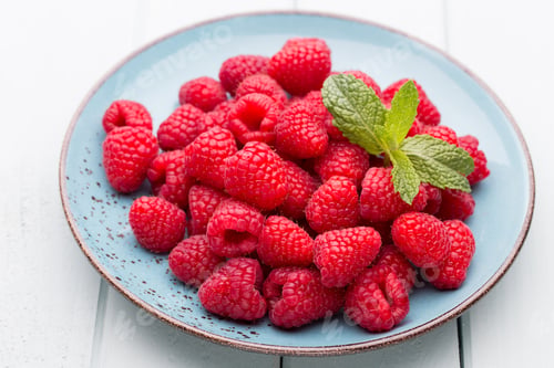 Preview: Fresh raspberries in a plate on a vintage background.