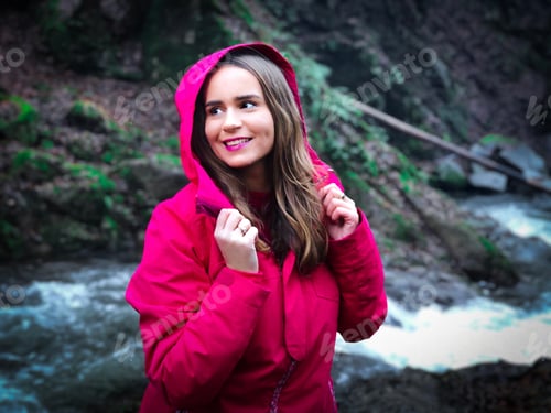 Preview: Portrait of young woman wearing sports jacket and standing near a river