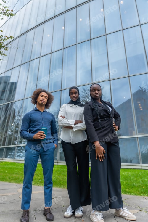 Preview: Diverse business team standing confidently in front of modern building