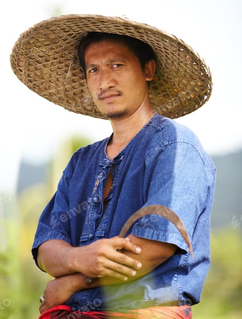Preview: Portrait of a Thai rice farmer holding a scythe and wearing a traditional hat