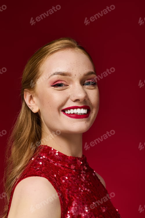 Preview: Beautiful young woman smiling brightly in a striking red sequined dress