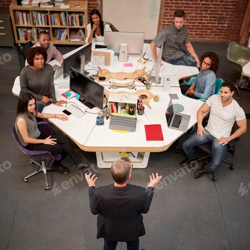 Preview: Senior Businessman Talking At Meeting Of Casually Dressed Business Team In Open Plan Office