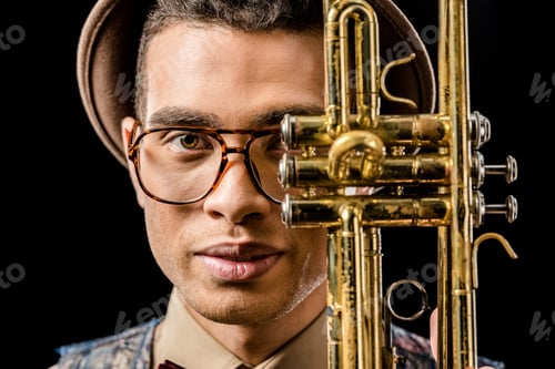 Preview: close up portrait of young male musician posing with trumpet isolated on black