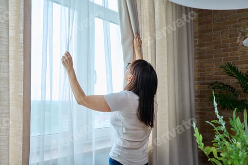 Preview: Back view, woman opens light curtains in the living room