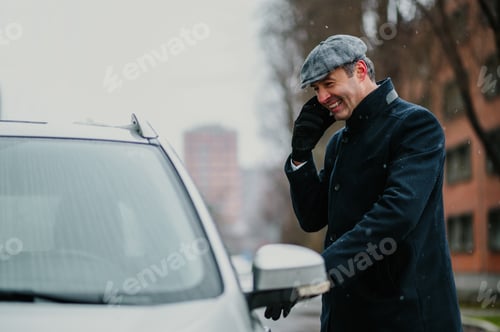 Preview: Elegant businessman is talking on the phone while entering his car
