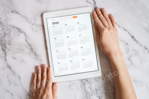 Preview: tablet computer with calendar for 2022 year, hands holding. flat lay. planning goals or to do list