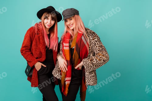 Vista previa: Two stylish blond women posing in studio on blue turquoise background.