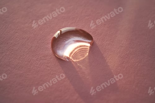 Preview: Beautiful volumetric drop of cosmetic product on a pink background.