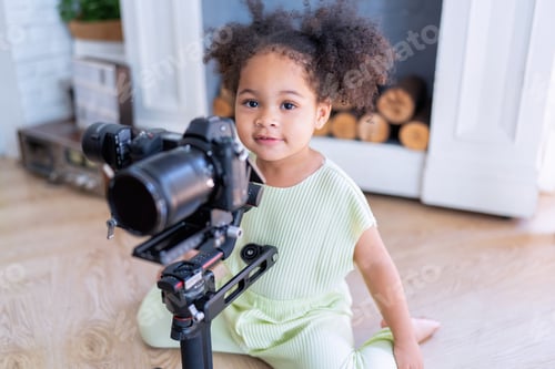 Preview: Little daughter sitting on the floor in the living room looking at camera on hand held gimbals