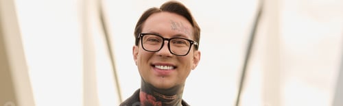 Preview: Stylish young man with tattoos poses confidently in a modern urban setting