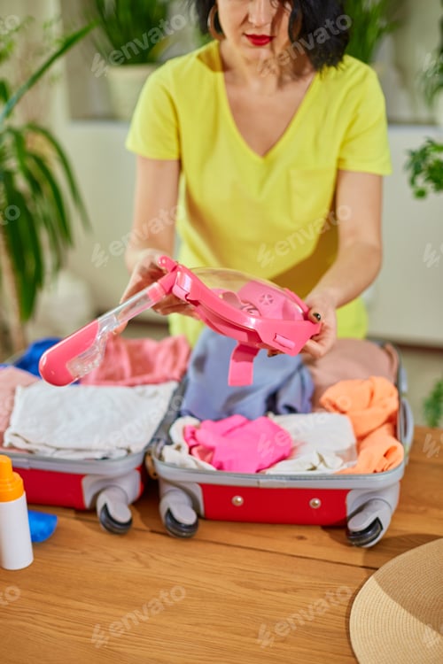 Preview: Woman hand packing suitcase, put snorkeling, diving mask