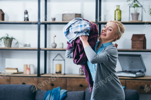 Preview: angry woman throwing clothes in living room after breaking up with boyfriend