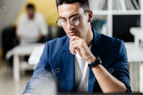 Preview: Professional young architect in glasses dressed in blue checkered jacket works on the laptop in the