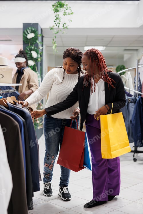 Preview: Two girlfriends browsing jackets display rack in shopping center