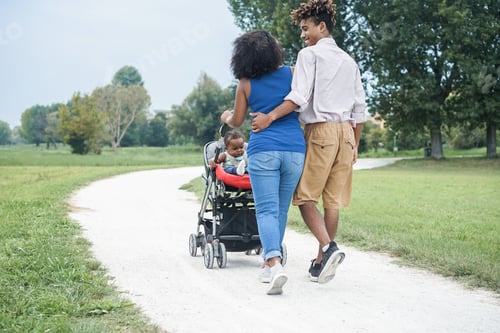 Preview: Happy black family having fun walking with stroller outdoor at city park - Focus on kid face