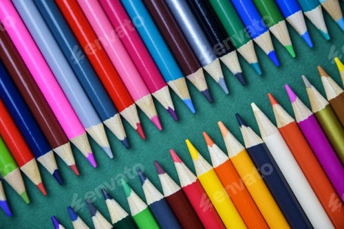 Preview: Color pencils on green background. Arrangement of multicolored pencils. Top view. Close-up.