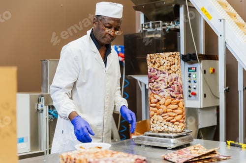 Preview: Warehouse worker weighing almonds during packaging process in a relaxed and proactive manner