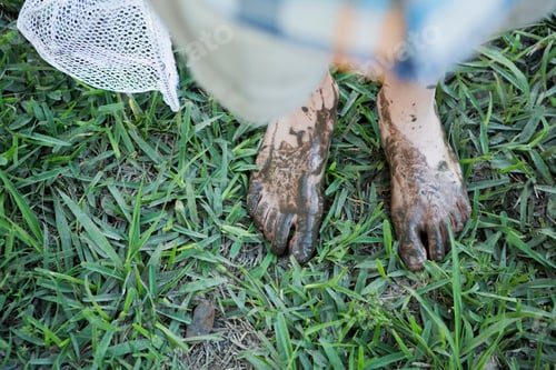 Preview: A boy with muddy feet standing on a river bank.