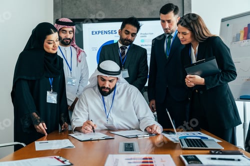 Preview: Multiethnic business team signing corporate agreement in dubai office