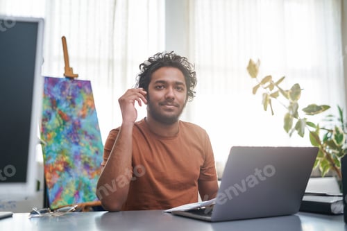 Preview: Cheerful indian designer looks at camera and poses in office