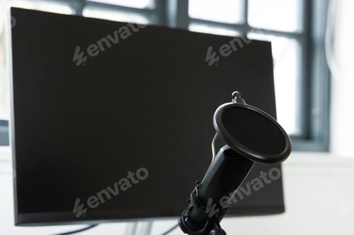 Preview: Microphone with pop filter in front of blank computer monitor at home