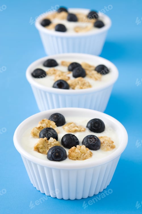 Preview: Three white bowls containing yogurt, blueberries and muesli creating a healthy breakfast