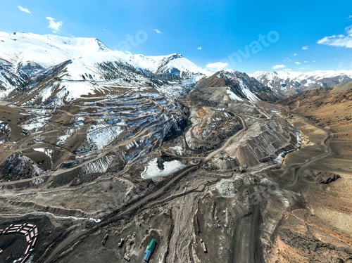 Preview: Panoramic view of an open pit mine complex and snowy mountain range