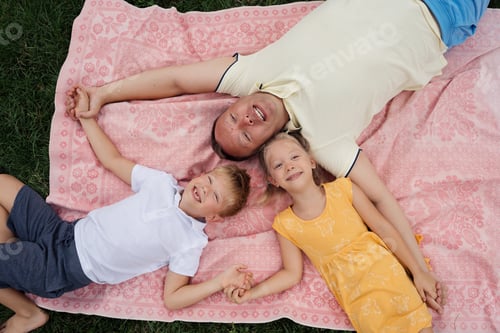 Vista previa: Familia feliz acostada en una manta disfrutando de un día de verano al aire libre