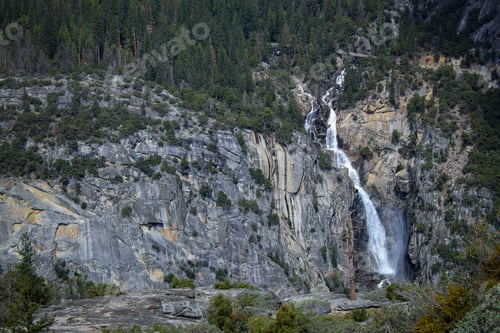 Preview: Majestic waterfall cascades down a rocky cliff, surrounded by lush trees and foliage