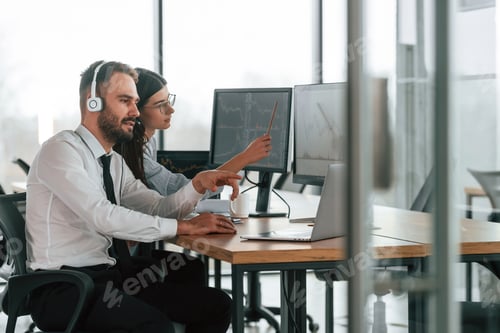 Preview: Man is in headphones. Two employees are working in the office together