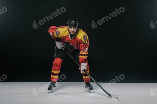 Preview: serious sportsman playing ice hockey and looking at camera on black