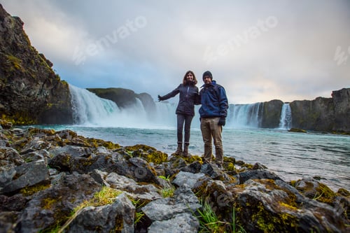 Preview: A young couple tourist looking at the Godafoss waterfall from above. Iceland