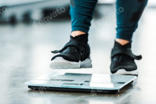 Preview: cropped view of plus size woman standing on scales