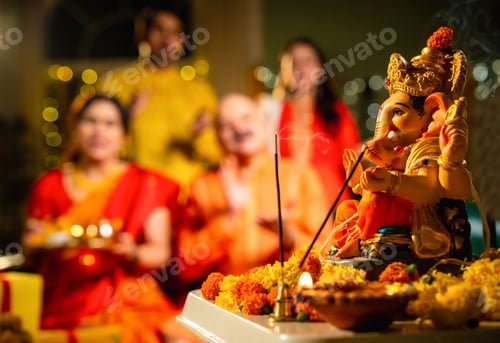 Preview: Indian family offering aarti to Ganpati idol at home with festive decor and traditional wear