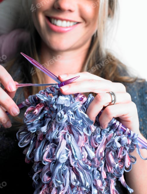Preview: Smiling woman enjoying her knitting time with colorful yarn