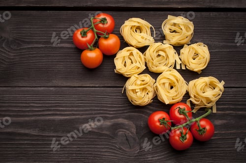 Preview: Raw spaghetti, cherry-tomatoes in the wooden background. Ingredients for Italian pasta. Top view