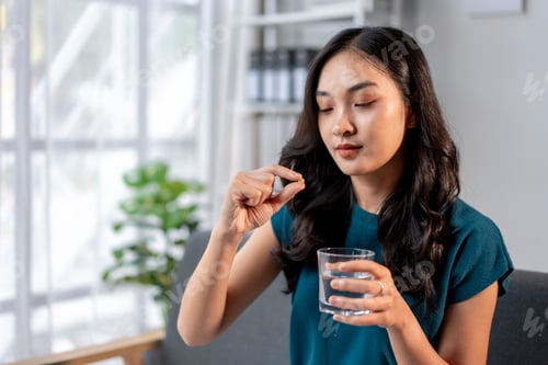 Preview: A woman is taking a pill and drinking water