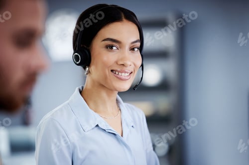 Preview: Shot of an attractive young call centre agent sitting with her colleague in the office