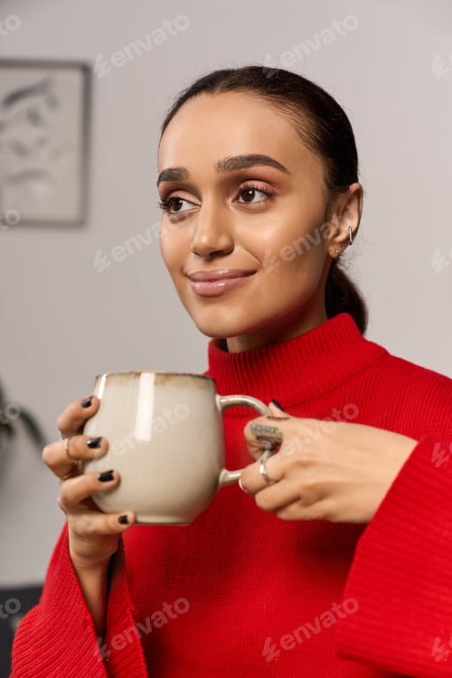 Preview: Young woman in a cozy red turtleneck enjoys a warm drink in a modern apartment