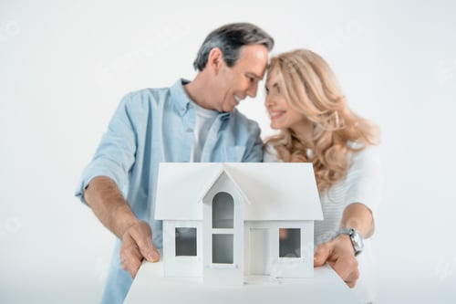 Preview: portrait of smiling mature couple showing house model isolated on white