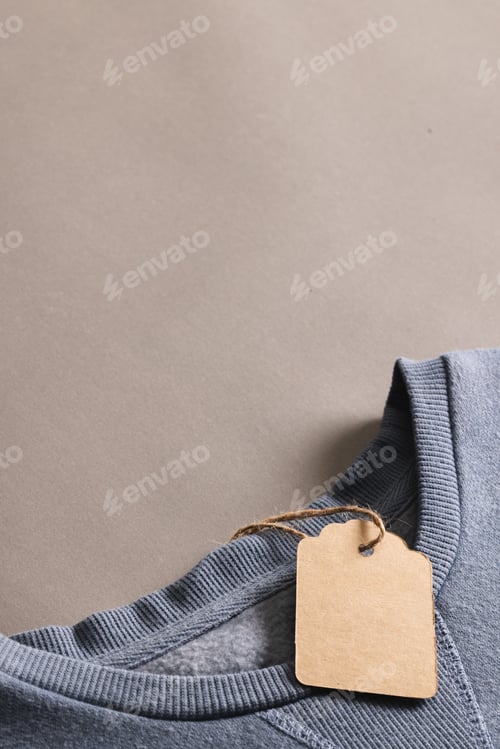 Preview: Close up of blue t shirt with tag and copy space on brown background