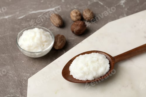Preview: Shea butter in wooden spoon and bowl with nuts on grey background