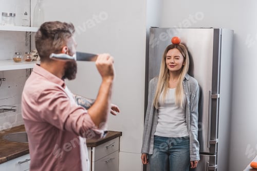 Preview: man throwing sharp knife at tomato on woman head