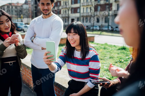 Preview: Young female and male adult friends using smartphones near city street