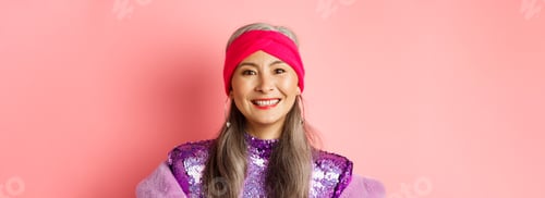 Preview: Close-up of trendy asian senior woman with grey hair and stylish disco dress, smiling happy at