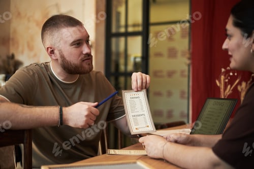 Preview: Caucasian Young Adult Man Discussing Menu Choices with Young Adult Woman